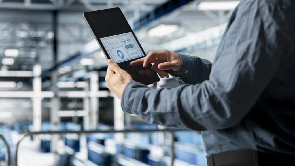 Servicetechniker prüft Auswertungen auf dem Tablet in einer Industriehalle